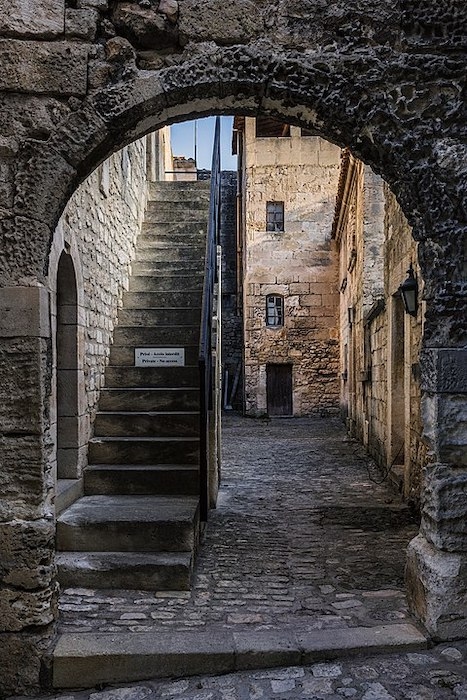 Un passage qui mène sur les escaliers extérieurs et dans une cour dans le village des Baux-de-Provence ©Christian Ferrer